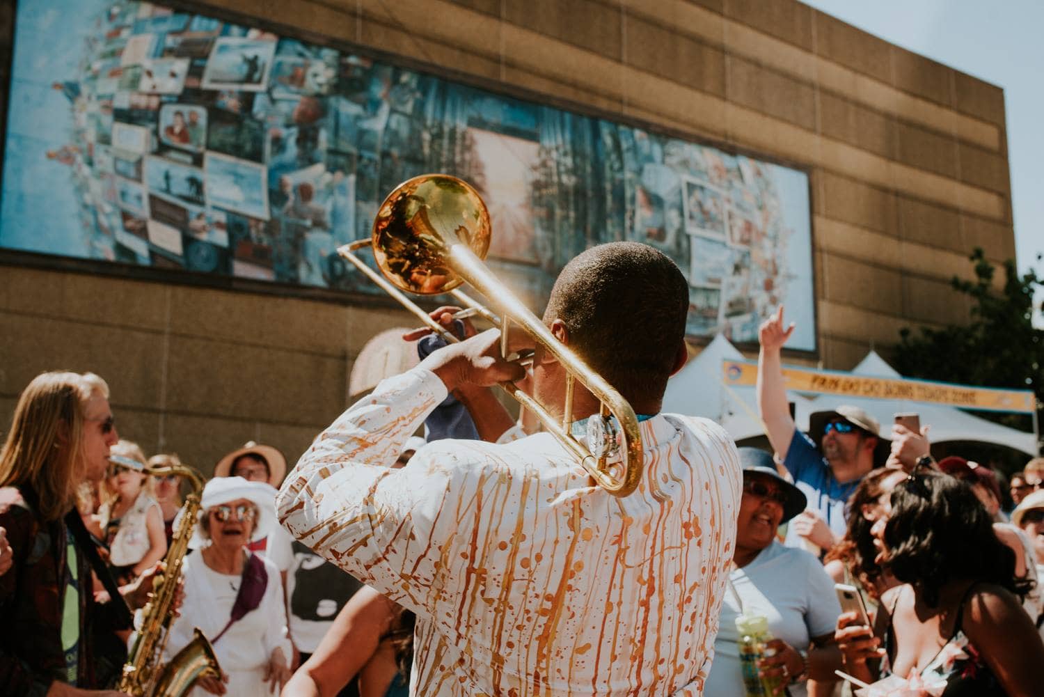 A man playing a trumpet in front of a mural